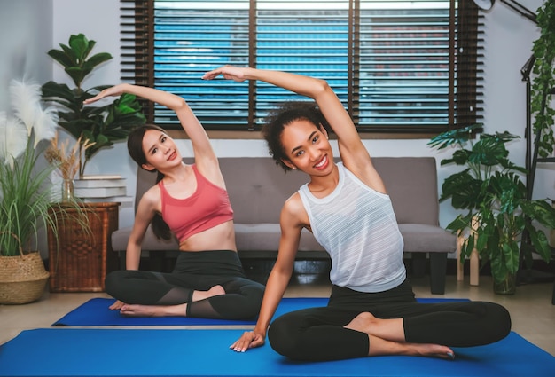 Junge erwachsene frauen, die zu hause mit freunden sport- und erholungskonzept yoga-übungen machen