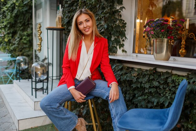 Junge europäische selbstbewusste Frau mit offenem Lächeln, das draußen in der Bar aufwirft