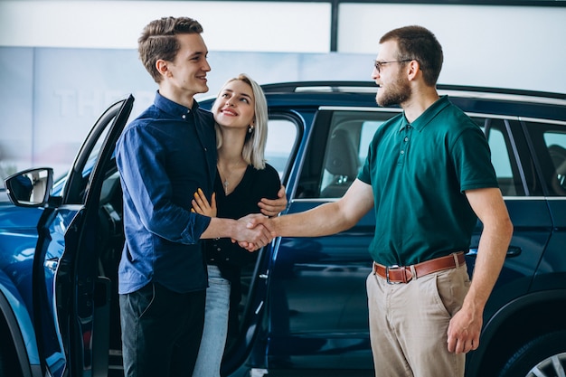 Kostenloses Foto junge familie, die ein auto in einem autosalon kauft