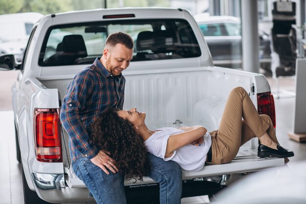 Junge Familie, die ein Auto in einem Autosalon wählt