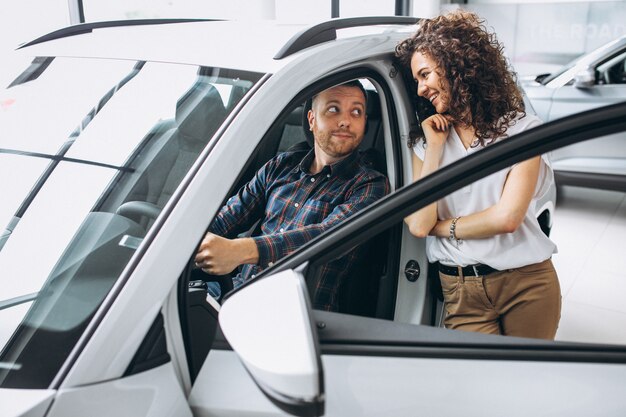 Junge Familie, die ein Auto in einem Autosalon wählt