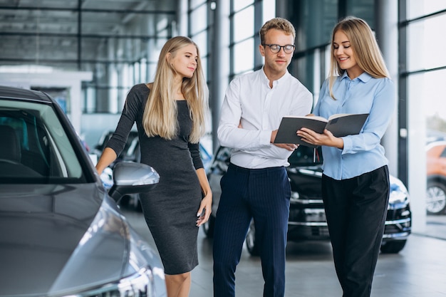 Junge Familie, die ein Auto in einem Autosalon wählt