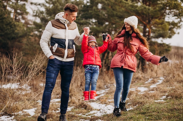 Junge Familie, die zusammen in Wald zur Winterzeit geht