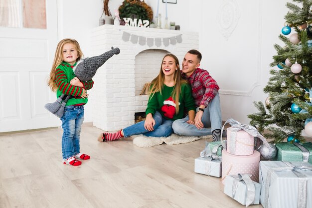 Junge Familie im Wohnzimmer mit Weihnachtsbaum