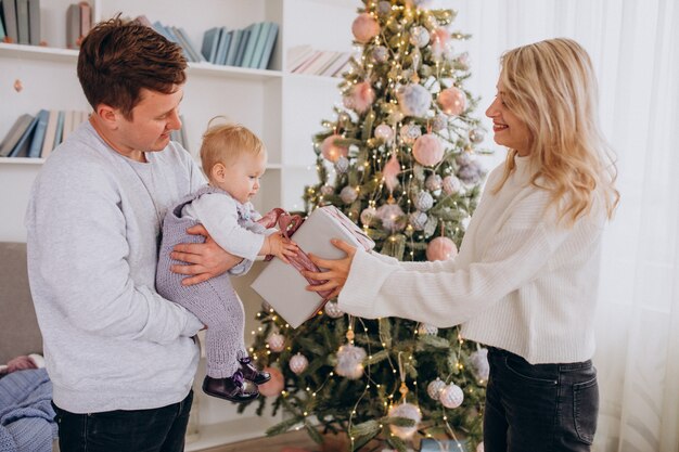 Junge Familie mit der kleinen Tochter, die Weihnachtsgeschenke hält