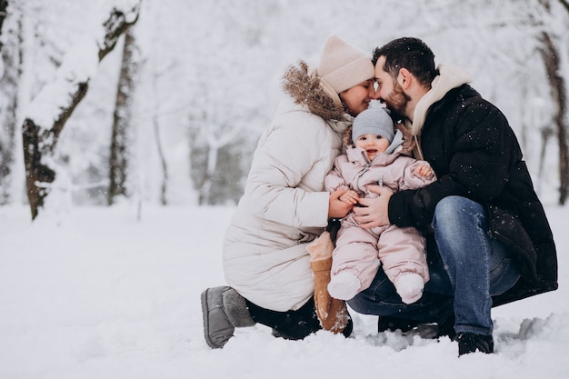 Junge Familie mit kleiner Tochter in einem Winterwald voll des Schnees