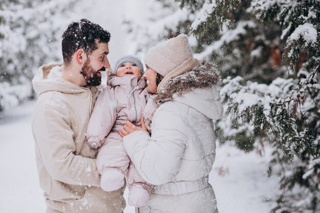 Junge Familie mit kleiner Tochter in einem Winterwald voll des Schnees