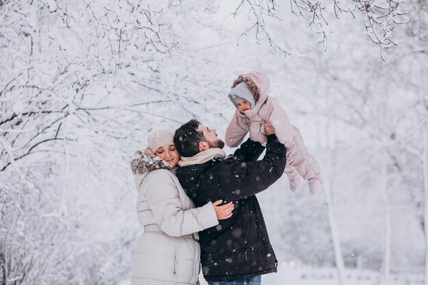 Junge Familie mit kleiner Tochter in einem Winterwald voll des Schnees