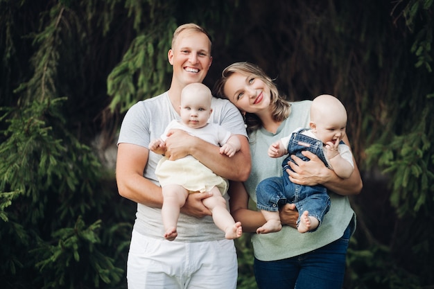 Junge Familie mit zwei Babys geht im Park spazieren und freut sich zusammen