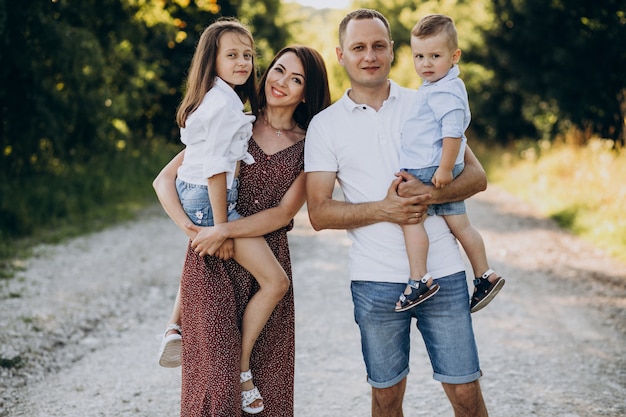 Kostenloses Foto junge familie mit zwei kindern, die die forststraße gehen