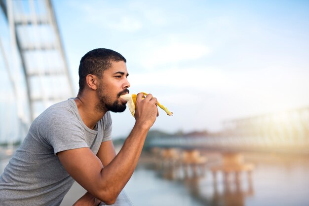 Junge fit sportliche Person, die Banane isst und lächelt