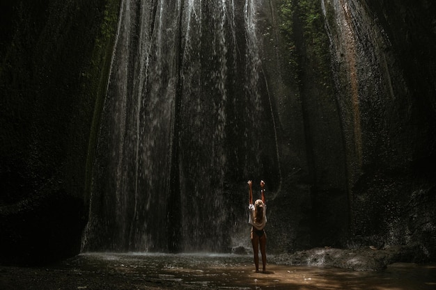 junge Frau am Wasserfall im Felsen Bali Indonesien
