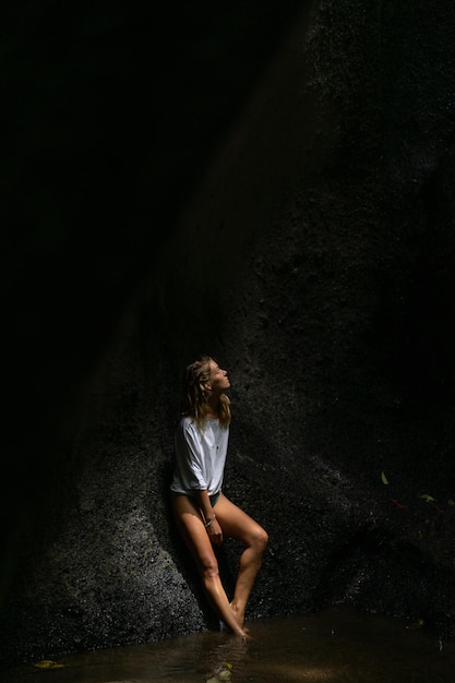 junge Frau am Wasserfall im Felsen Bali Indonesien
