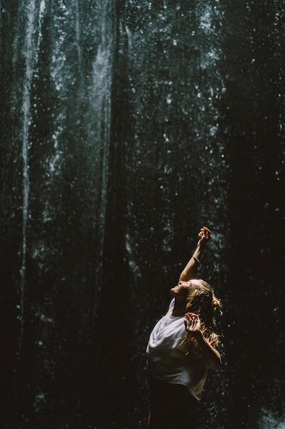 Kostenloses Foto junge frau am wasserfall im felsen bali indonesien