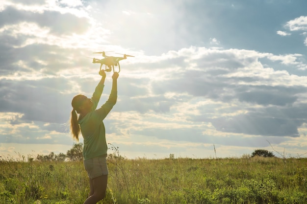 Junge Frau auf einem Feld startet die Drohne in den Himmel