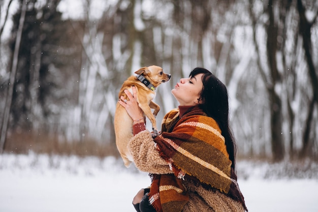 Junge frau außerhalb des parks mit ihrem kleinen hund am winter