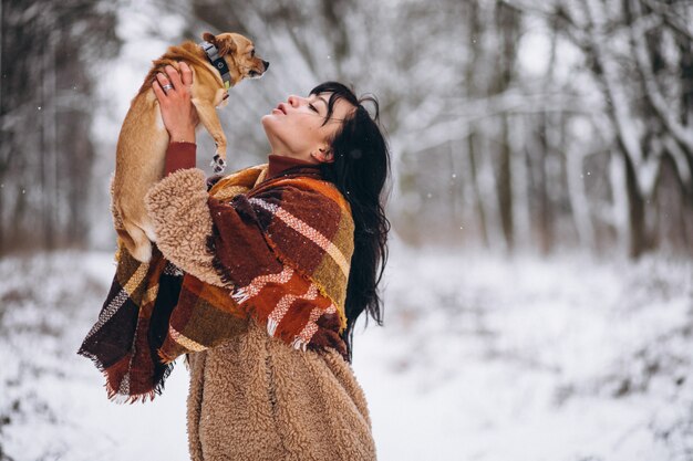 Junge Frau außerhalb des Parks mit ihrem kleinen Hund am Winter
