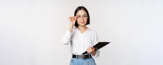 Junge Frau, Büroangestellte, Managerin mit Brille, die Klemmbrett hält und wie ein professioneller Standin aussieht