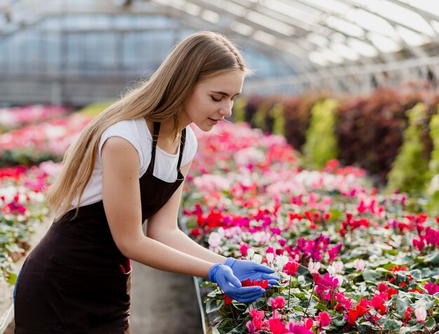 Junge Frau der Seitenansicht, die Blumen betrachtet