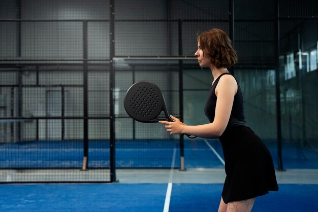 Junge Frau der Seitenansicht, die Paddle-Tennis spielt