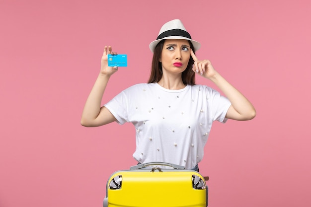 Junge frau der vorderansicht, die bankkarte auf den rosa wandausflugfrauensommergefühlen hält