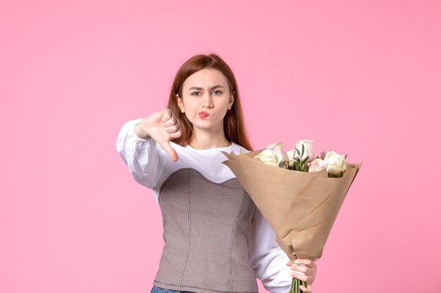 Junge Frau der Vorderansicht, die Blumenstrauß von schönen Rosen auf Rosa hält