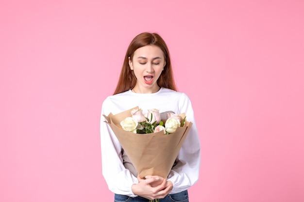 Junge Frau der Vorderansicht, die Blumenstrauß von schönen Rosen auf Rosa hält