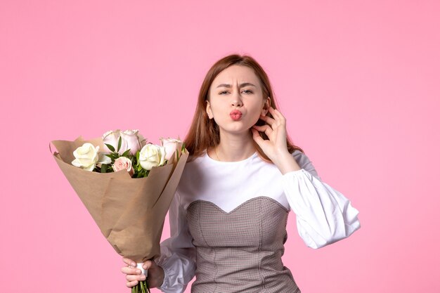 Junge Frau der Vorderansicht, die Blumenstrauß von schönen Rosen auf Rosa hält