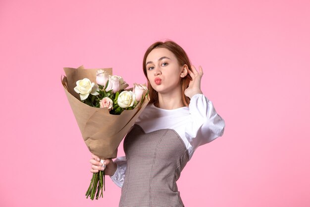 Junge Frau der Vorderansicht, die Blumenstrauß von schönen Rosen auf Rosa hält