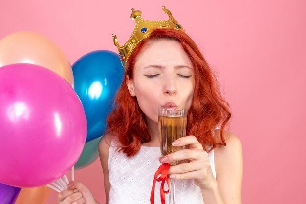 Junge Frau der Vorderansicht, die bunte Luftballons auf dem Rosa hält