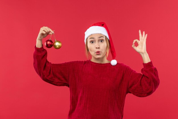 Junge Frau der Vorderansicht, die mit Weihnachtsspielzeug auf rotem Schreibtischfeiertagsweihnachtsgefühl aufwirft