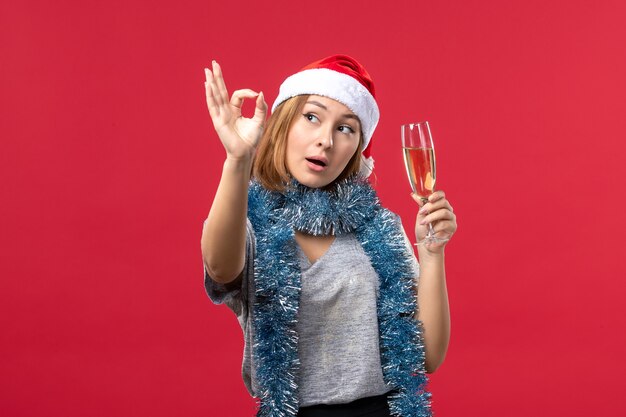 Junge Frau der Vorderansicht, die neues Jahr auf Weihnachtsfeiertag der roten Bodenfarbe feiert