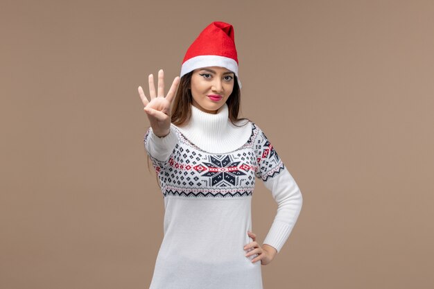 Junge Frau der Vorderansicht, die Nummer auf Weihnachtsemotion des braunen Hintergrundfeiertags zeigt