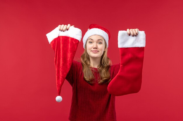 Junge Frau der Vorderansicht, die rote große Socke und Kappe hält, rotes Weihnachten des Feiertags