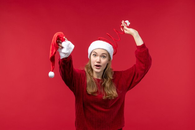 Junge Frau der Vorderansicht, die rote Kappe, Weihnachtsfeiertagweihnachten hält