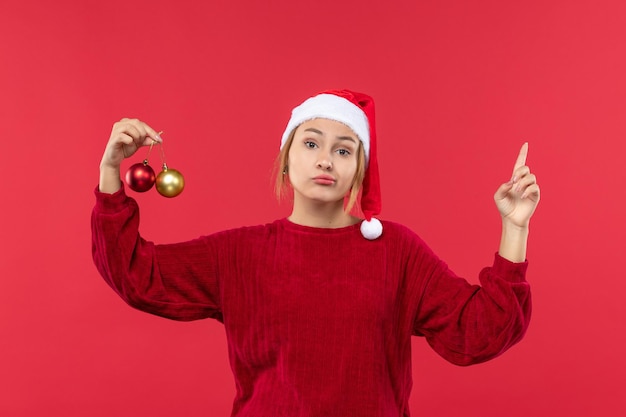 Junge Frau der Vorderansicht mit Weihnachtsballspielwaren, Feiertagsweihnachtsrot