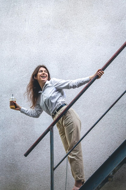 Kostenloses Foto junge frau des geschäfts nahe der treppe mit einer tasse kaffee