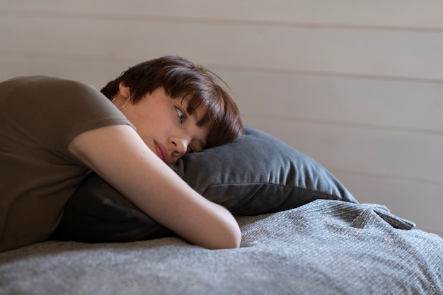 Junge Frau des mittleren Schusses, die im Bett legt