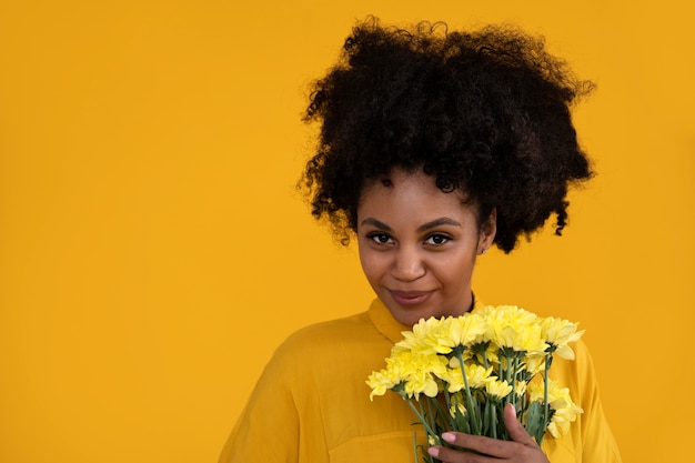 Kostenloses Foto junge frau des mittleren schusses, die mit blumen aufwirft