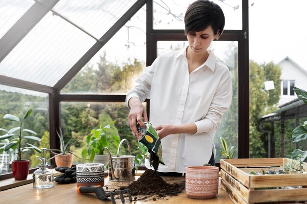 Junge Frau des mittleren Schusses mit Blumenerdebeutel