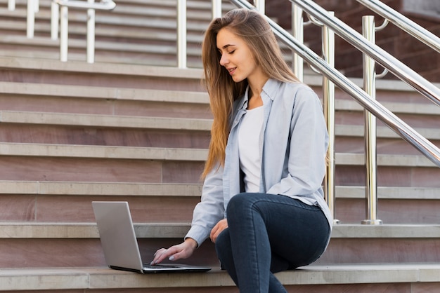 Junge Frau des niedrigen Winkels, die an Laptop arbeitet