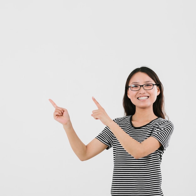 Junge Frau des smiley, die oben mit Kopienraum zeigt