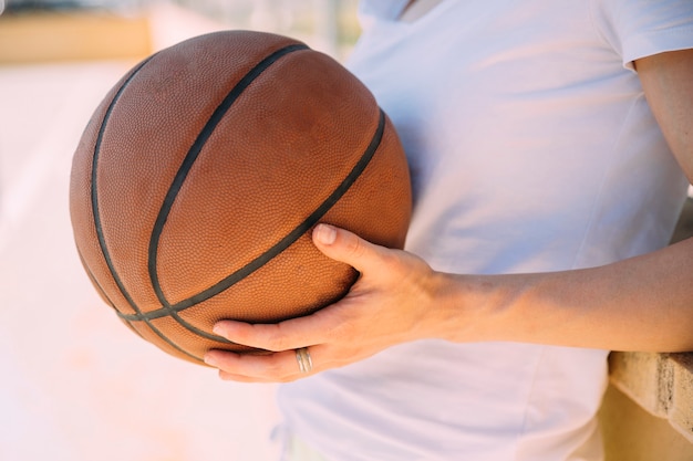 Junge Frau, die am Basketballplatz steht