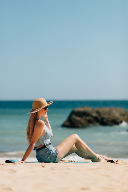 Junge Frau, die am Meeresstrand sitzt