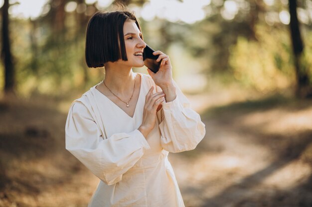 Junge Frau, die am Telefon im Park spricht