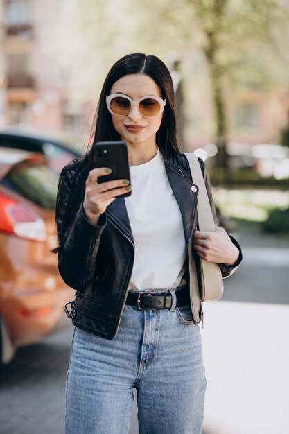 Junge Frau, die am Telefon spricht und in der Stadt geht