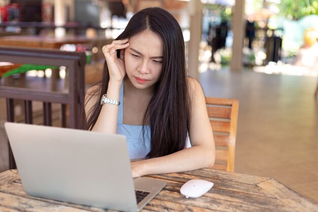 Junge Frau, die an dem Laptop hat Kopfschmerzen arbeitet.