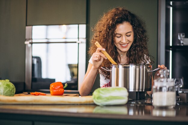 Junge Frau, die an der Küche kocht