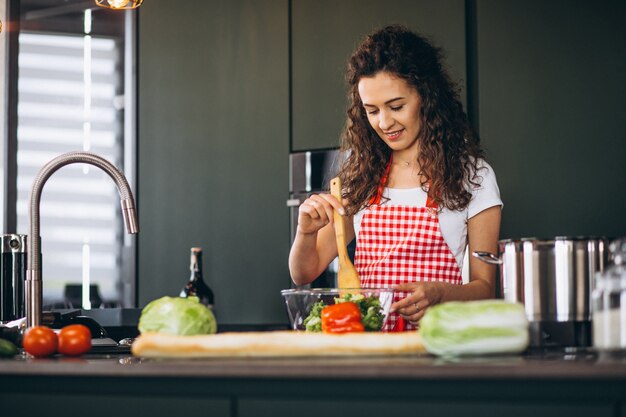 Junge Frau, die an der Küche kocht