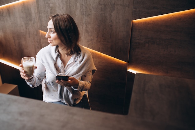 Junge Frau, die an der Rezeption sitzt und Kaffee trinkt